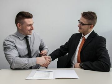 two men facing each other while shake hands and smiling