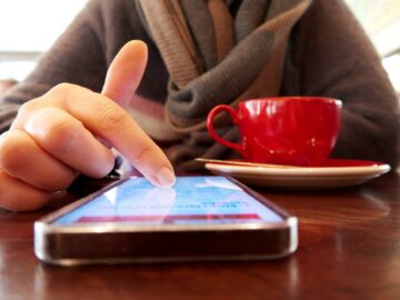 Person using a smartphone with a cup of coffee.