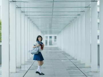 Schoolgirl poses in a white hallway.