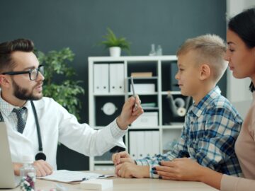 Doctor examines a young boy with his mother present.
