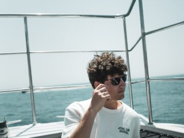 A man sitting on top of a boat next to the ocean