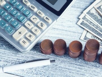 a calculator, pen, and money on a table
