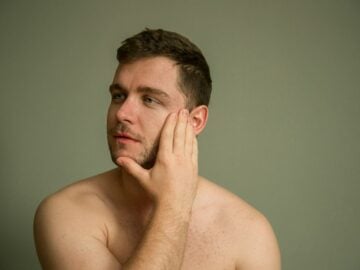 topless man covering his face with his hand. men skincare mistakes