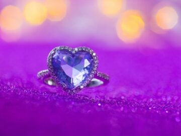Heart-shaped purple gemstone ring on sparkly fabric. what does purple mean on a mood ring