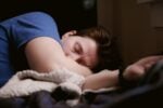 woman in blue shirt lying on bed. Is Sleep Apnea a Disability