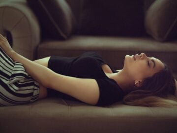 woman in black and white stripe shirt lying on brown couch. Sleeping and Drooling