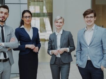 Four professionals in business attire stand together.