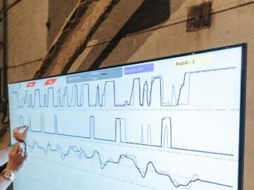 a woman points to a chart on a large screen