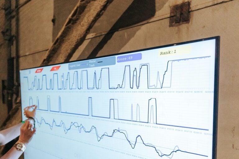a woman points to a chart on a large screen