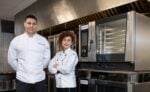 a couple of people standing in front of some ovens