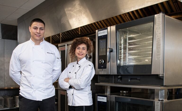 a couple of people standing in front of some ovens