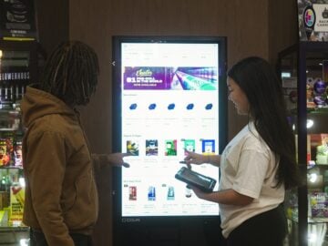 Two people interact with a digital display screen.
