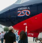 People gather around a plane with "america 250" logo.
