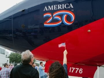 People gather around a plane with "america 250" logo.