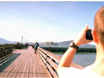 Man takes a picture of a pier and island