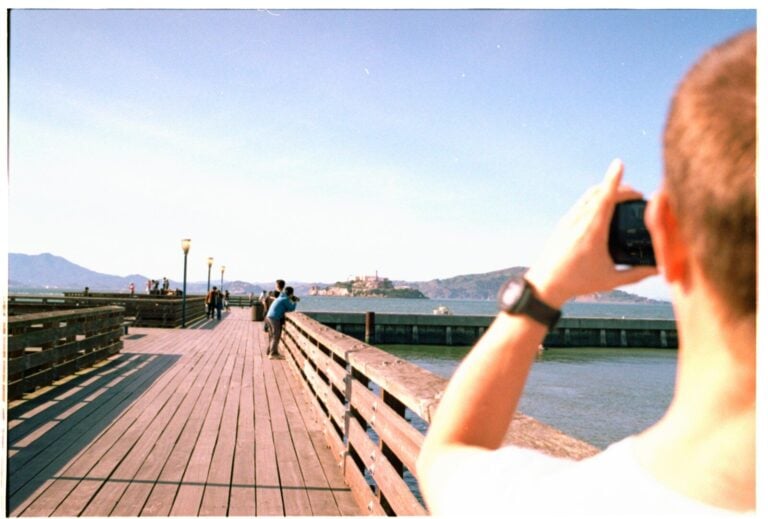 Man takes a picture of a pier and island