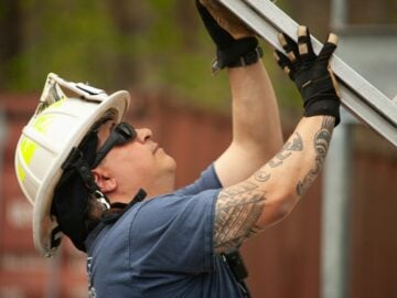Firefighter in helmet adjusts metal scaffolding outdoors